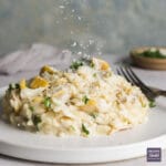 Creamy smoked haddock risotto piled neatly on a small plate, with parmesan being sprinkle on top.