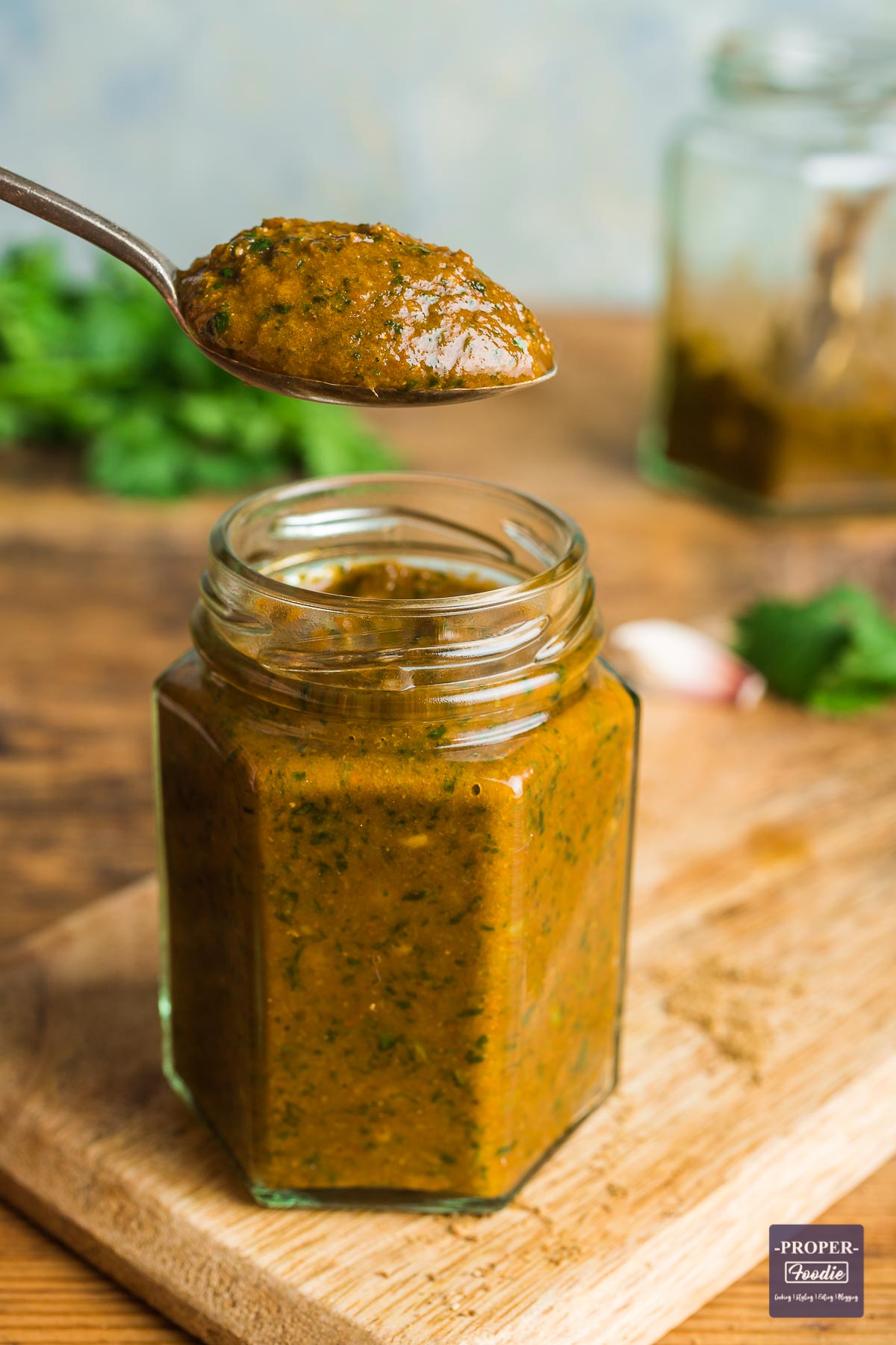 Tikka masala paste in a jar with a teaspoonful of paste hovering above the jar.