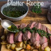 Slices of medium-rare steak positioned over a pile of cubed rosemary potatoes with a herb and chilli dressing being spooned over the top.