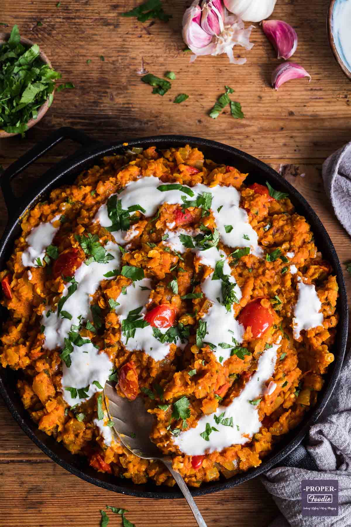 Lentil dahl in a wide skillet pan and topped with yogurt and parsley.