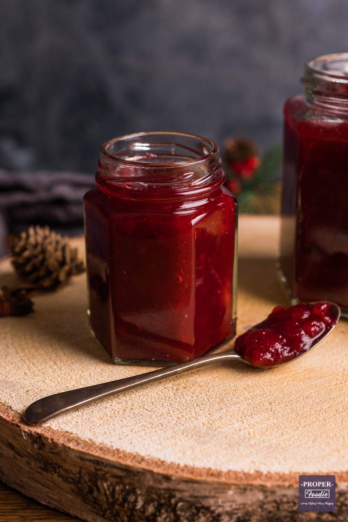 Small jar filled with homemade cranberry sauce with a spoonful of sauce at the side.