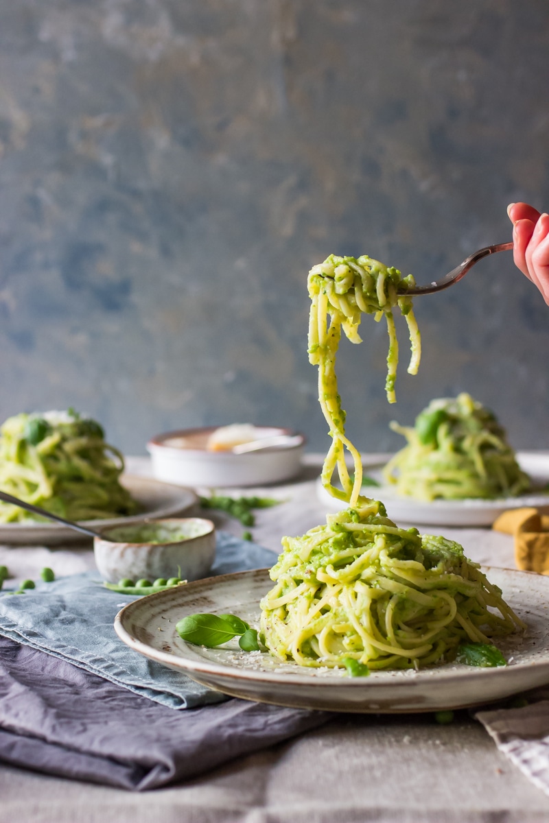 pea pasta made with a cream pea pesto served on a plate with pasta being lifted with fork