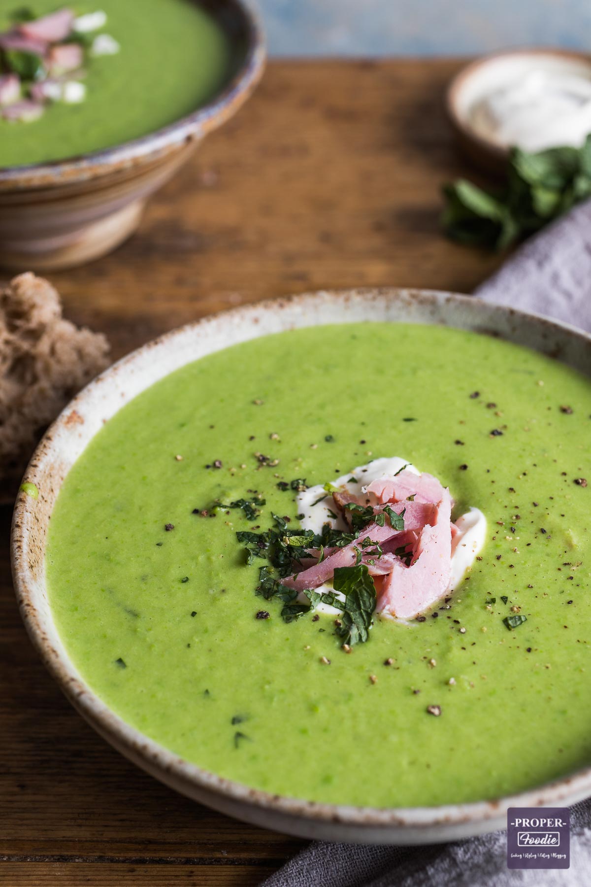 pea and ham soup in a bowl with creme fraishe, mint leaves and ground black pepper.