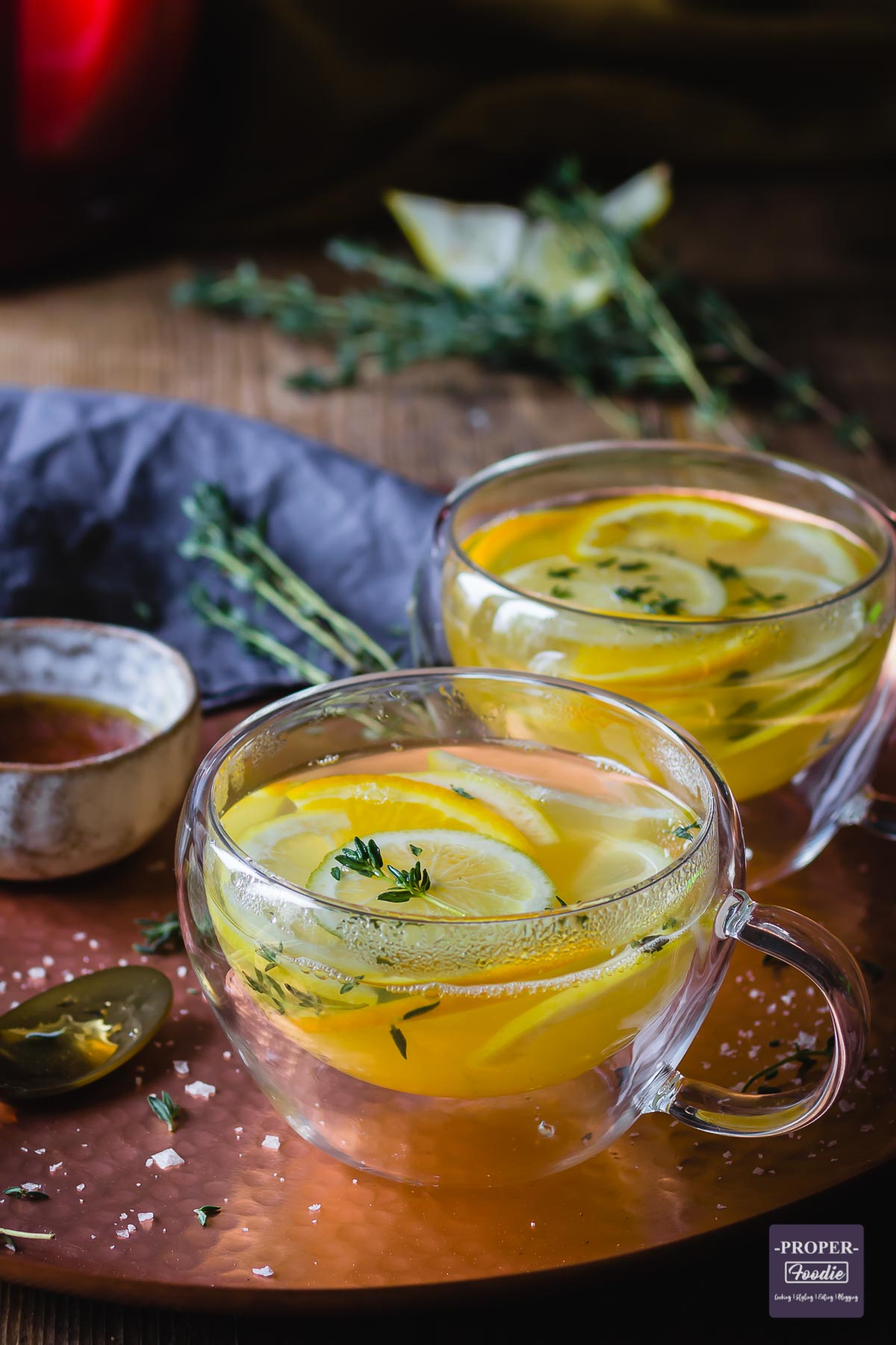 Steamy cup of lemon tea in a glass teacup sat on a bronze mottled tray.