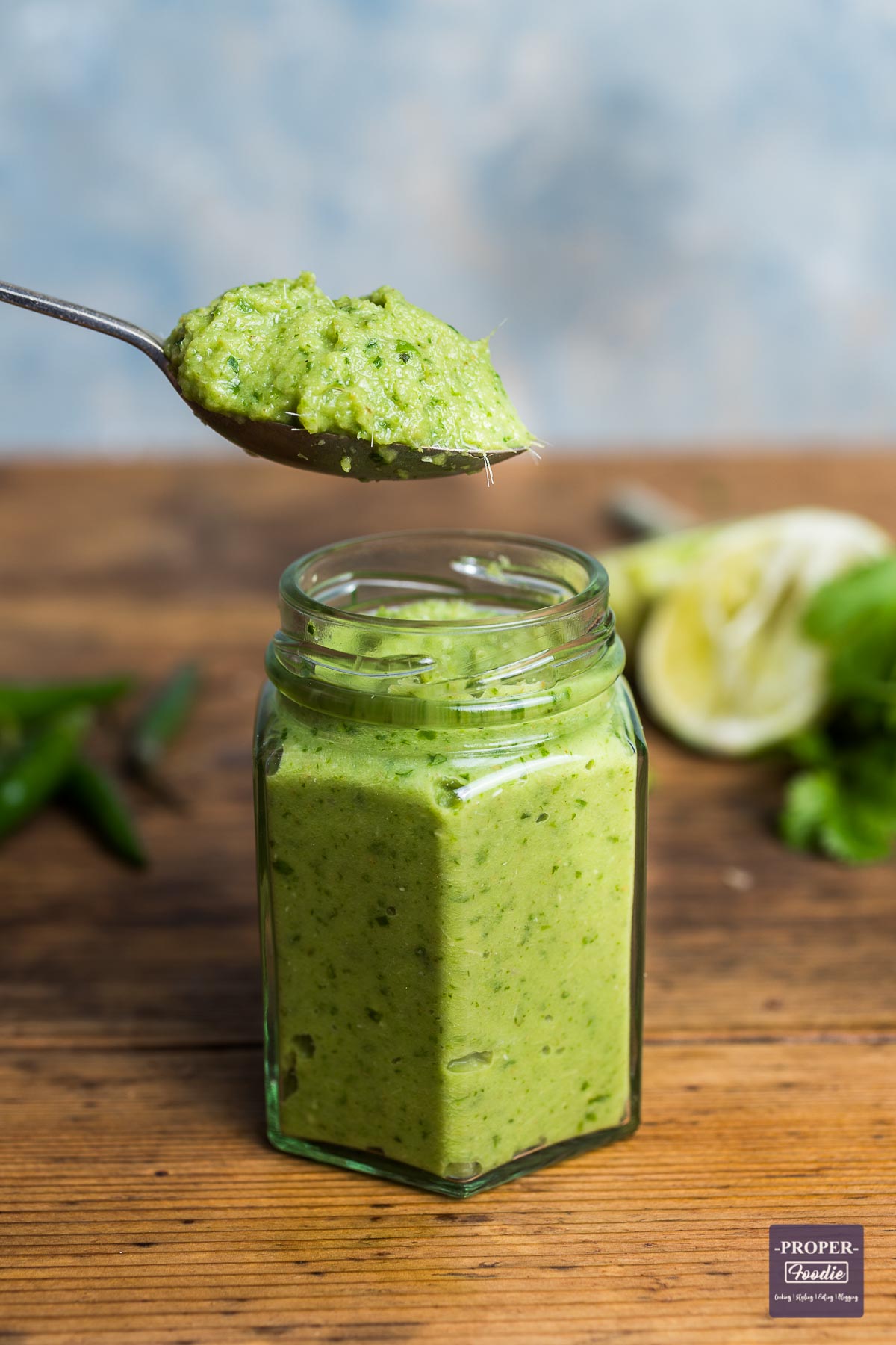 A small jar filled with home Thai green curry paste with teaspoon of paste being held above the jar.