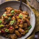 Chinese dragon chicken recipe in a bowl and topped with spring onions.
