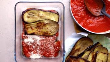 continuing to layer aubergine with tomato sauce and parmesan