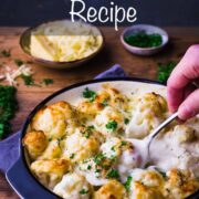 Cauliflower presented in a shallow dish with a creamy sauce and topped with baked on cheese and freshly chopped parsley.