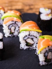 four pieces of sushi with slices of salmon and avocado on the top to mimic a dragon