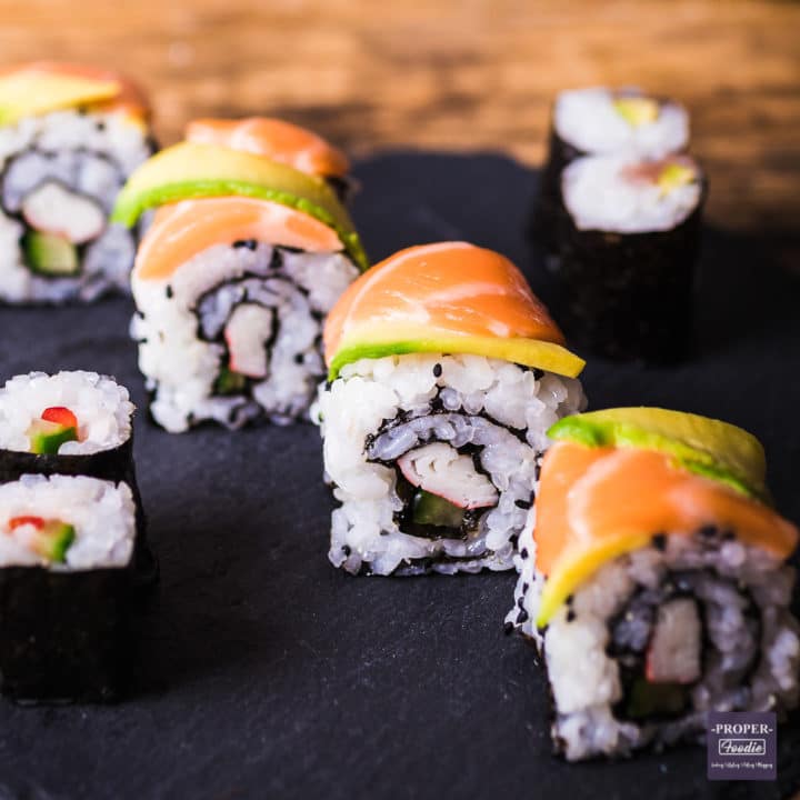 four pieces of sushi with slices of salmon and avocado on the top to mimic a dragon