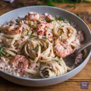 A bowl of linguine in a creamy sauce with salmon and prawns.