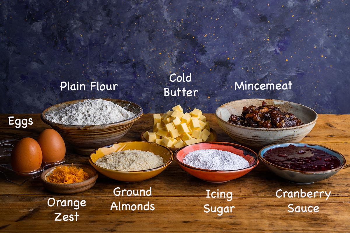 A display of all the ingredients needed to make mince pies with text overlay labelling each ingredient.