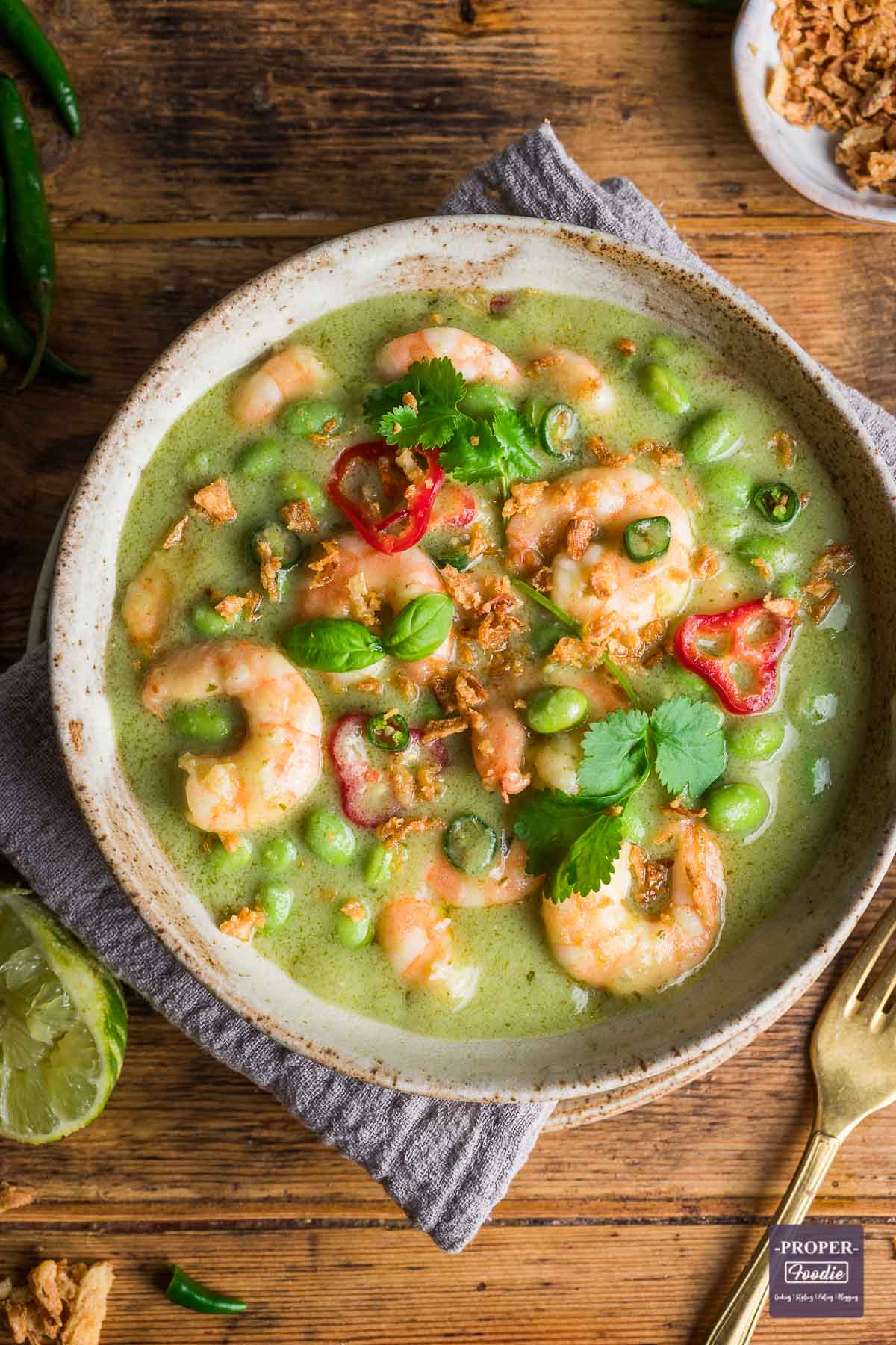 Thai green prawn curry served in a bowl and topped with fresh basil and chillies.